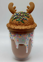 Three Christmas-themed cups with antler lids and sprinkle frosting in festive setup