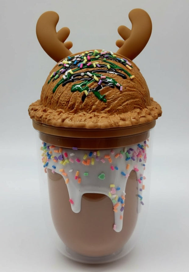 Three Christmas-themed cups with antler lids and sprinkle frosting in festive setup